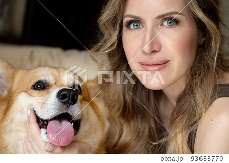 young woman with cute corgi dog smiling looking at camera close up portrait 93633770