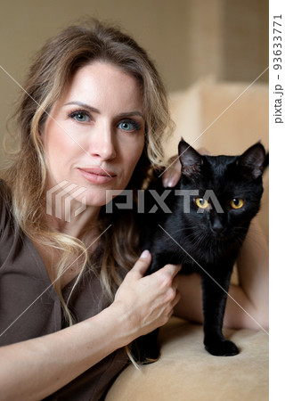 young woman posing with cute black cat with yellow eyes in her hands close up portrait young woman posing with cute black cat with yellow eyes in her hands close up portrait 93633771
