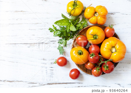 Raw organic vegetables. The concept of vegan or diet food. Fresh ripe bunch colorful tomatoes, red, yellow on a wooden table. View from above. Copy space. Raw organic vegetables. The concept of vegan or diet food. Fresh ripe bunch colorful tomatoes, red, yellow on a wooden table. View from above. Copy space. 93640264