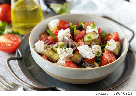 Healthy vegetarian diet food. Salad with grill eggplants, tomatoes and feta cheese on a gray stone tabletop. 93640313