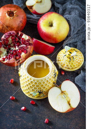 The concept of Rosh hashanah (Jewish New Year). Traditional holiday symbols - shofar, honey, apple and pomegranate on a stone or slate background. Flat lay, top view. The concept of Rosh hashanah (Jewish New Year). Traditional holiday symbols - shofar, honey, apple and pomegranate on a stone or slate background. Flat lay, top view. 93640317