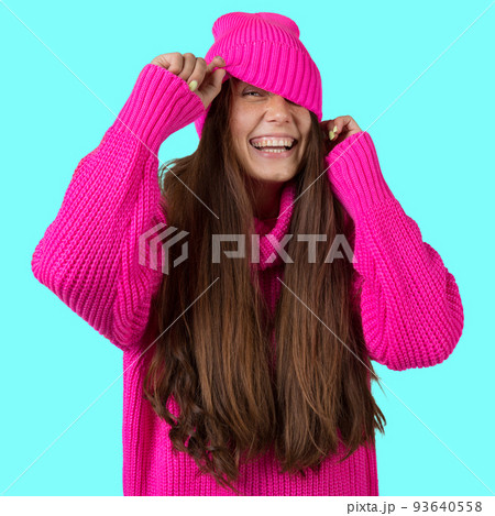 A young girl with long hair, in a crimson knitted sweater and a crimson hat, laughs merrily, peeking out from under the cap, concept A young girl with long hair, in a crimson knitted sweater and a crimson hat, laughs merrily, peeking out from under the cap, concept 93640558