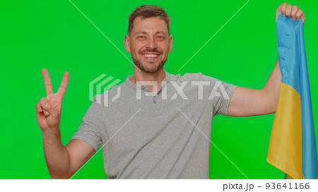 Young man hold Ukraine national flag, showing victory sign against war, hoping for success and win 93641166