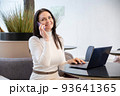 Smiling woman working on laptop and smartphone 93641365