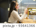 woman in medical mask in public place. portrait of woman in cafe typing smartphone 93641366