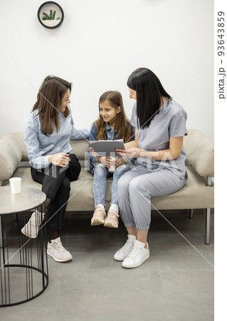 Medical worker communicates with a young mother and her daughter in the waiting room of the clinic 93643859