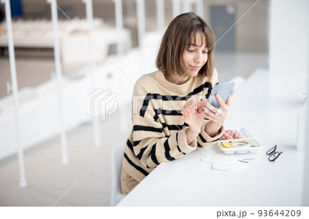 Young woman using phone while sitting at restaurant Young woman using phone while sitting at restaurant 93644209