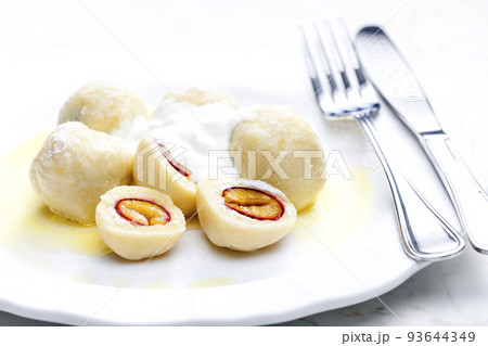 plum dumplings with sour cream, powder sugar and melted butter 93644349