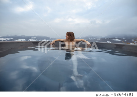Woman bathing in hot tub at mountains Woman bathing in hot tub at mountains 93644391