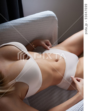 young woman in transparent lingerie posing against studio background. 93647699