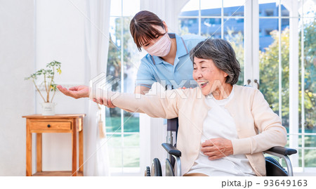 リハビリテーションセンター　ストレッチをする高齢女性とサポートするケアスタッフ 93649163