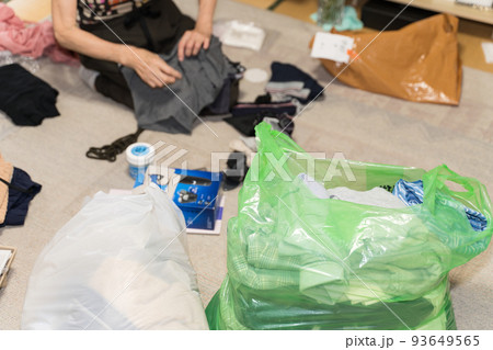 不要になった衣類をゴミ袋に入れて捨てるシニア女性　遺品整理 93649565