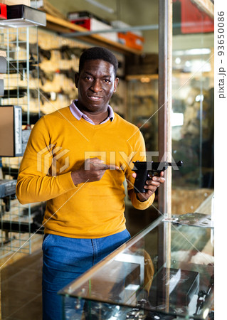 African american man chooses and buys pistol at gun store 93650086