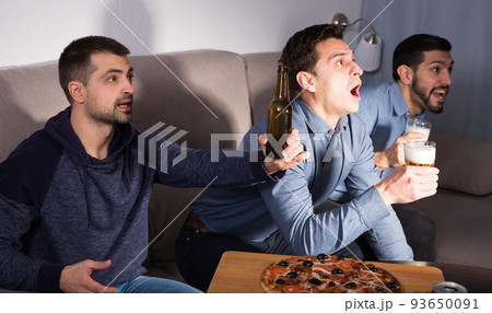 Happy men emotionally watching tv with beer and pizza at home 93650091