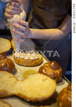 A baker fills brioche cream in a craft bakery. A close-up photo. Vertical photo. A baker fills brioche cream in a craft bakery. A close-up photo. Vertical photo. 93651769