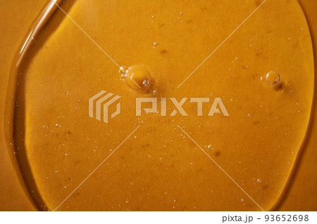 A drop of body gel or shampoo on a yellow saturated background. Texture. A drop of body gel or shampoo on a yellow saturated background. Texture. 93652698