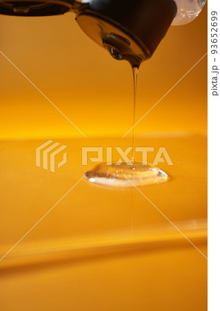A drop of body gel or shampoo pouring from above on a yellow saturated background. A drop of body gel or shampoo pouring from above on a yellow saturated background. 93652699