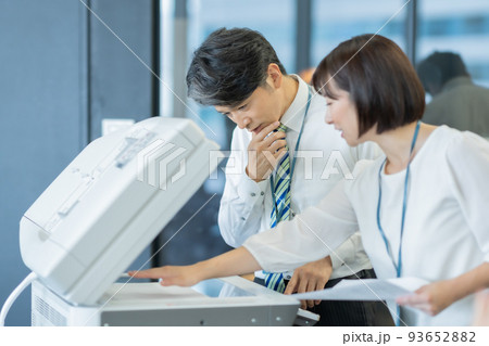 コピー機の使い方をベテランに教える女性スタッフ コピー機の使い方をベテランに教える女性スタッフ 93652882