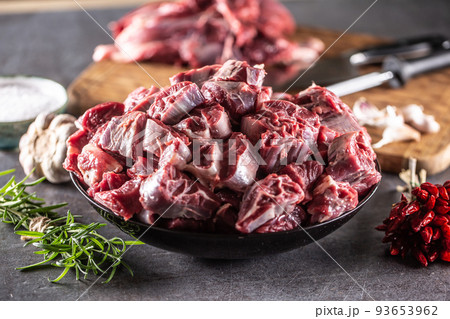 Fresh beef shank cuts piled in a bowl on a dark surface with herbs and spices around Fresh beef shank cuts piled in a bowl on a dark surface with herbs and spices around 93653962