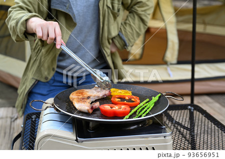Cropped shot of woman grilled bbq and preparing food for dinner during camping in nature park on beautiful day Cropped shot of woman grilled bbq and preparing food for dinner during camping in nature park on beautiful day 93656951