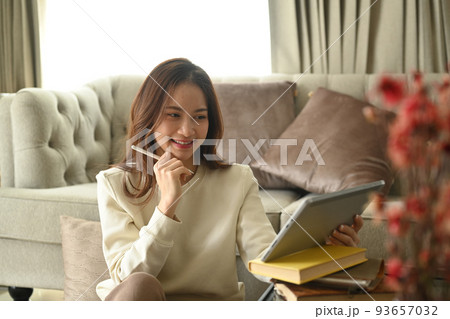 Happy woman wearing sweater checking social media or email on her digital tablet in bright winter morning 93657032