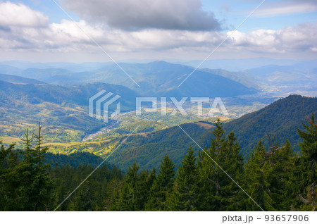 mountain landscape on a sunny autumn morning. village in the distant valley. view from the top of a forested hill mountain landscape on a sunny autumn morning. village in the distant valley. view from the top of a forested hill 93657906