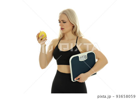 Sporty woman with apple and scales isolated on white background Sporty woman with apple and scales isolated on white background 93658059