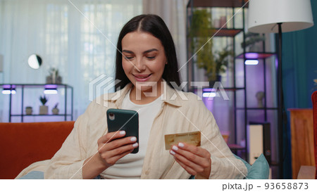 Lovely girl using credit bank card and smartphone, transferring money, purchases online shopping Lovely girl using credit bank card and smartphone, transferring money, purchases online shopping 93658873