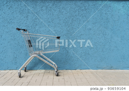 Supermarket cart trolley on empty colored wall background. Retail, sale, shopping concept.  93659104