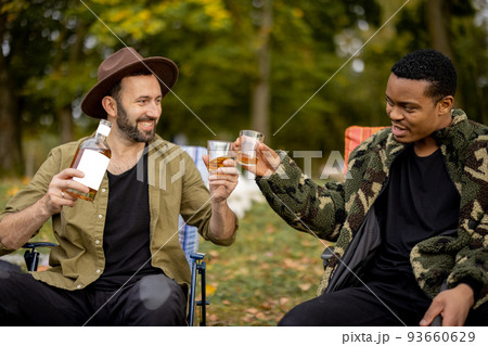 Two male friends fishing with alcoholic drinks Two male friends fishing with alcoholic drinks 93660629