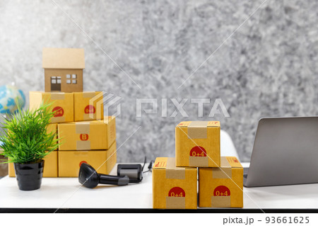 Cardboard parcel box with barcode scanner and laptop on desk at workplace of startup small business owner for online selling. Cardboard parcel box with barcode scanner and laptop on desk at workplace of startup small business owner for online selling. 93661625