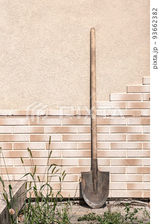 Old dirty filthy shovel against the tile wall summer day Old dirty filthy shovel against the tile wall summer day 93662382