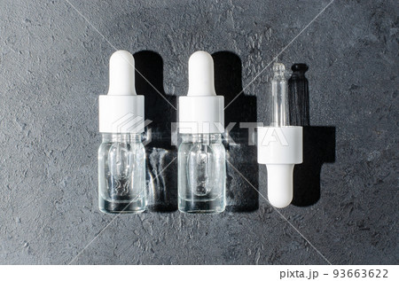 Cosmetic product in a bottle with a pipette. Serum for skin or hair. Black concrete background. 93663622