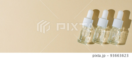 Cosmetic product in a bottle with a pipette. Serum for skin or hair. Flat layout. Beige background. Copy space. 93663623
