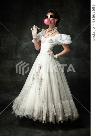 Youth style. Young pretty woman as medieval renaissance style lady having fun isolated on dark vintage background. Concept of funny meme emotions 93665699