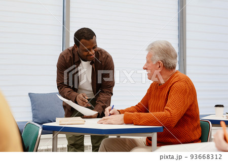 Teacher explaining material to senior man Teacher explaining material to senior man 93668312