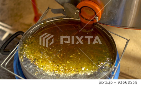 Honey in a metal tank flows through a pipe. Honey is filtered through a sieve after extraction. 93668558