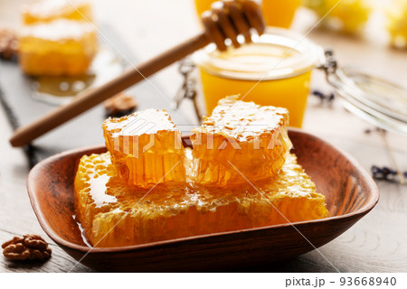 Honeycomb on slate tray with honey and nuts on kitchen table Honeycomb on slate tray with honey and nuts on kitchen table 93668940