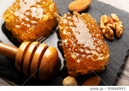 Honeycomb on slate tray with honey and nuts on kitchen table 93668943