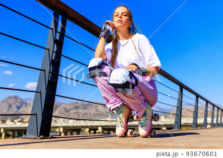 Happy woman with long blonde braids hair on the roller-skate in the park beach and mountain background 93670601