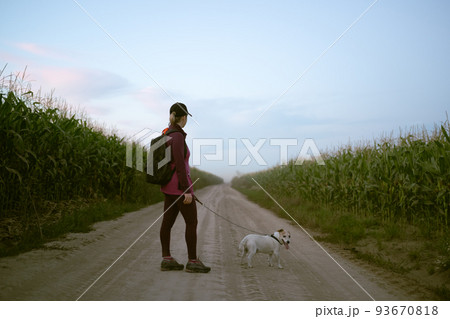 Girl and dog walking on rural road 93670818
