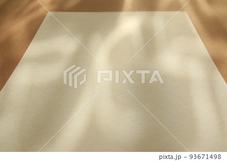 empty white paper sheet on brown background with sunlight glow and shadows empty white paper sheet on brown background with sunlight glow and shadows 93671498