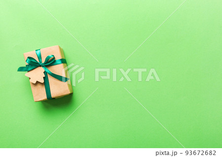 wrapped christmas or other holiday handmade present in paper with colored ribbon. Present box, decoration of gift on colourfull table, top view with copy space 93672682
