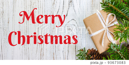 Merry Christmas text. Christmas background with Christmas gift on wooden background with Fir branches. Xmas and Happy New Year composition. top view Merry Christmas text. Christmas background with Christmas gift on wooden background with Fir branches. Xmas and Happy New Year composition. top view 93673083