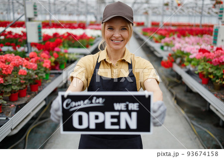Female garden worker holding an open signboard 93674158