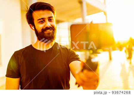 bearded man in black cotton t-shirt recording video for vegan blog outdoor in summer park at sunset gold light bearded man in black cotton t-shirt recording video for vegan blog outdoor in summer park at sunset gold light 93674268