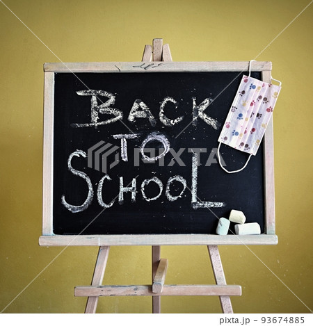 Blackboard - back to school. Concept for education and school on yellow background. With a mask to protect against covid 19. Blackboard - back to school. Concept for education and school on yellow background. With a mask to protect against covid 19. 93674885