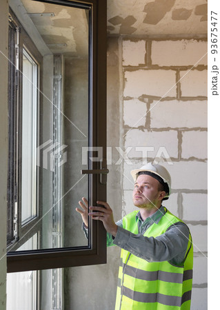 male chief engineer in the room make measurements of windows, specialists in the installation and replacement of double-glazed windows. male chief engineer in the room make measurements of windows, specialists in the installation and replacement of double-glazed windows. 93675477