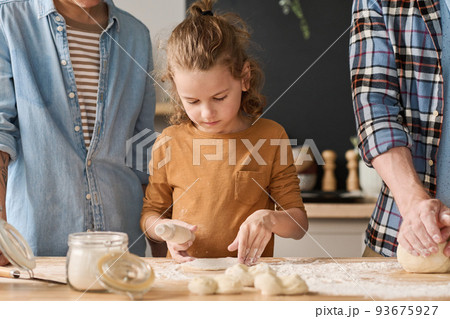 Little boy learning to bake pie from dough together with his parents at table 93675927