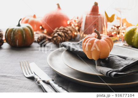 Thanksgiving day dinner decorated fallen leaves, pumpkins, spices, grey plate. 93677104